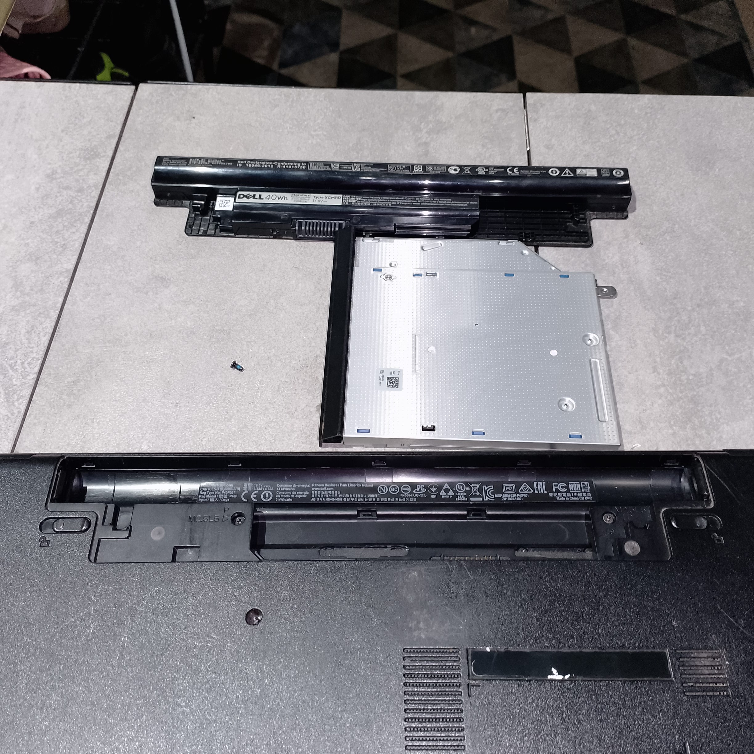 Извлечённый DVD-привод Dell P40F рядом с аккумулятором