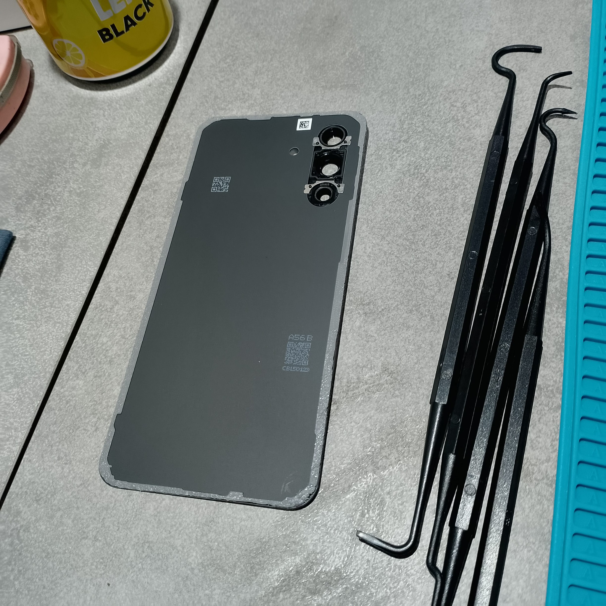 Samsung Galaxy A56 замена дисплея - Старая задняя крышка уже снята. Видны блок камер и набор пластиковых лопаток, которыми удобнее проходить клей