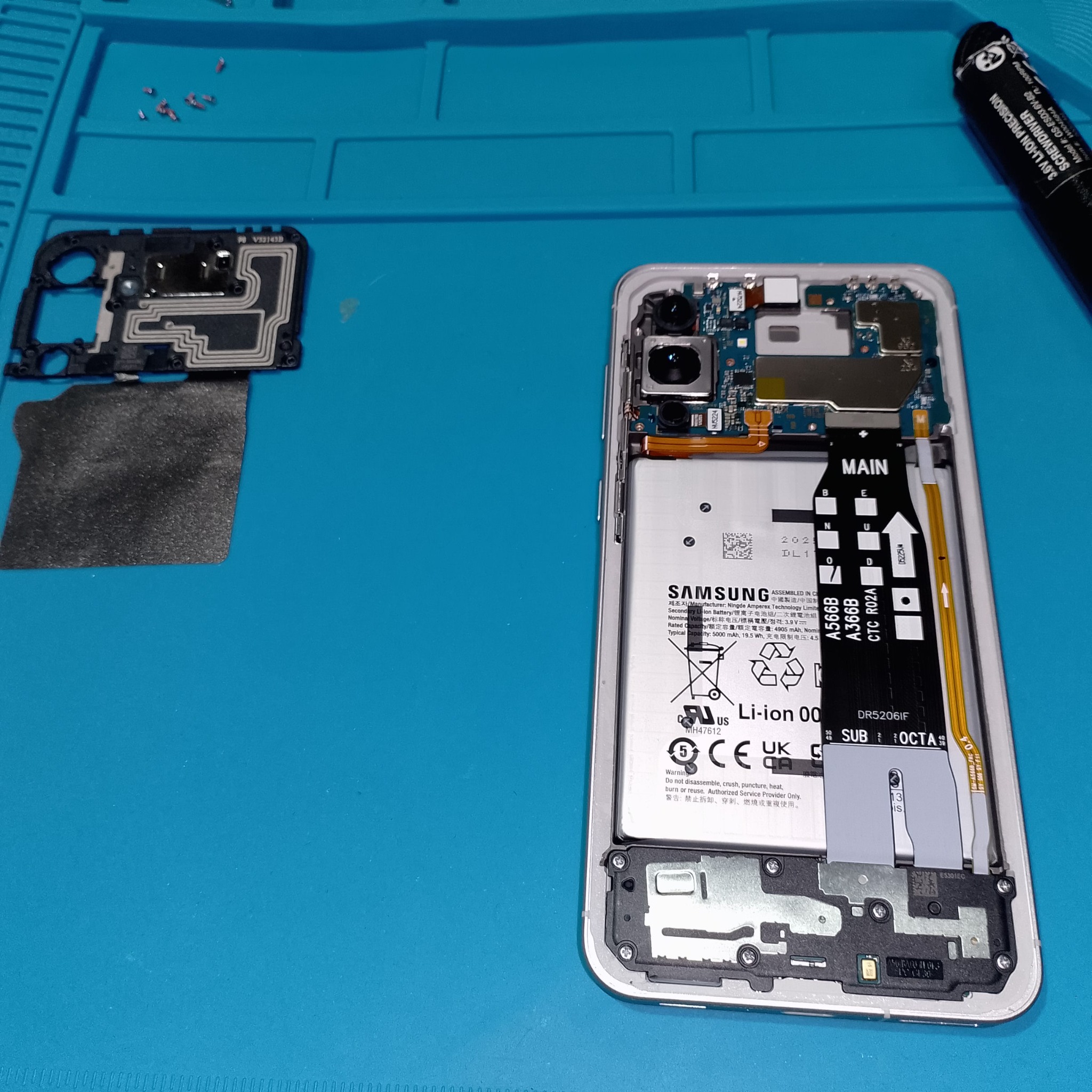 Samsung Galaxy A56 замена дисплея - Верхняя защитная накладка с антеннами лежит отдельно, смартфон открыт до платы и аккумулятора. После этого мож