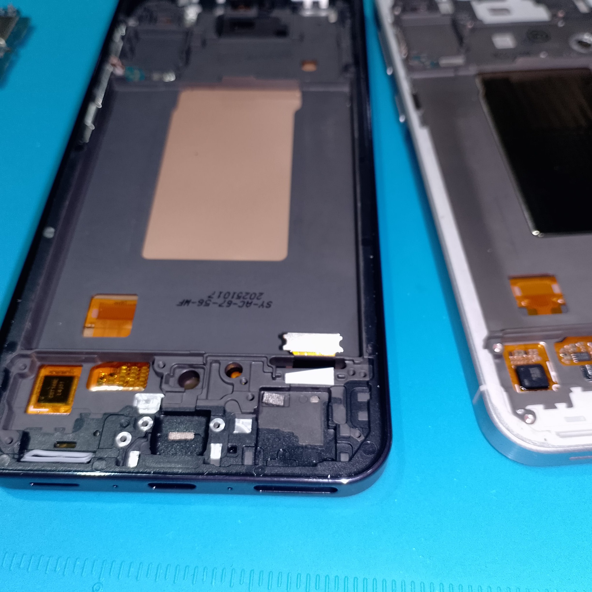 Samsung Galaxy A56 замена дисплея - Старая и новая рамки лежат рядом нижней частью. Перед переносом удобно сравнить отверстия, посадочные места и