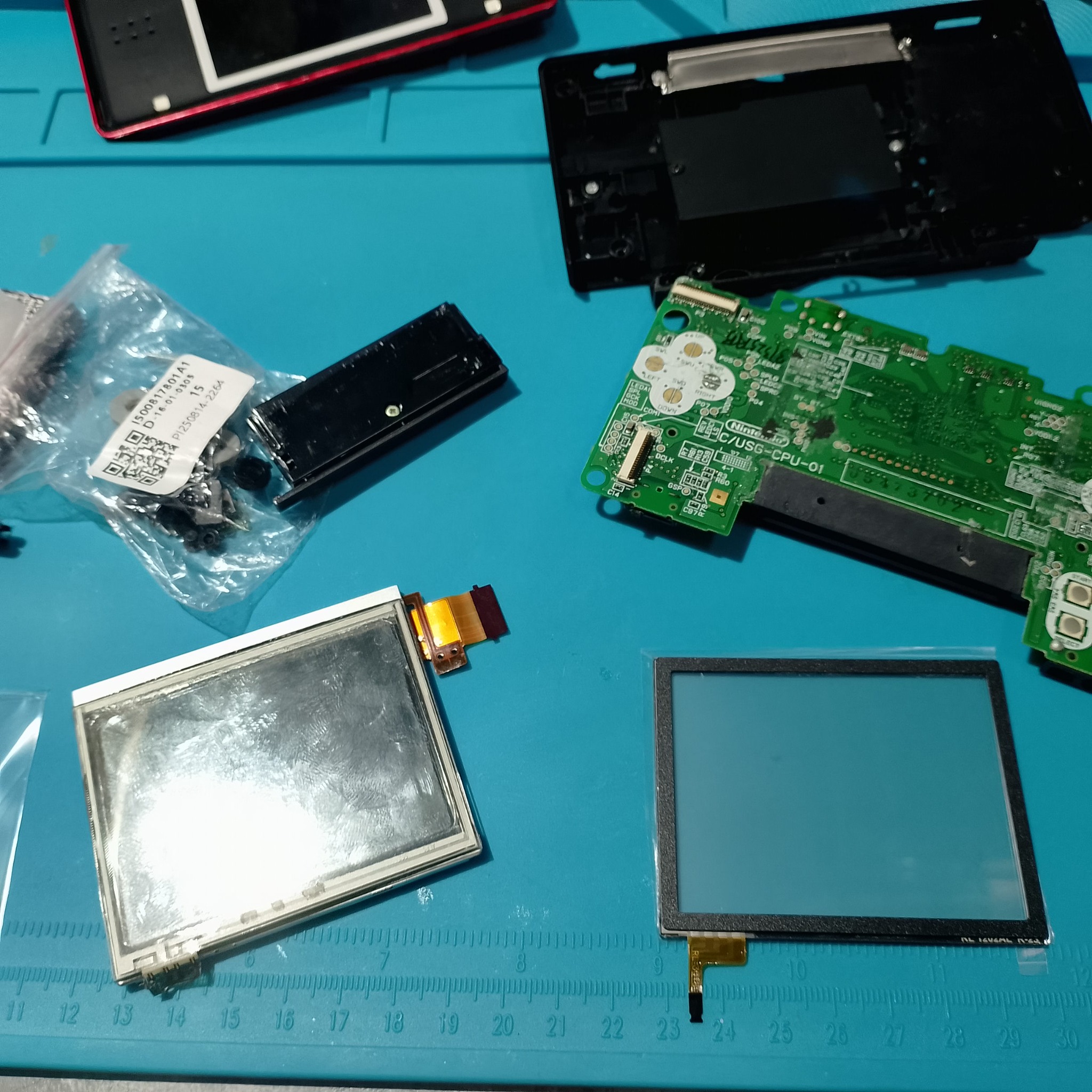 Дисплей и сенсорный слой Nintendo DS Lite разложены перед сборкой