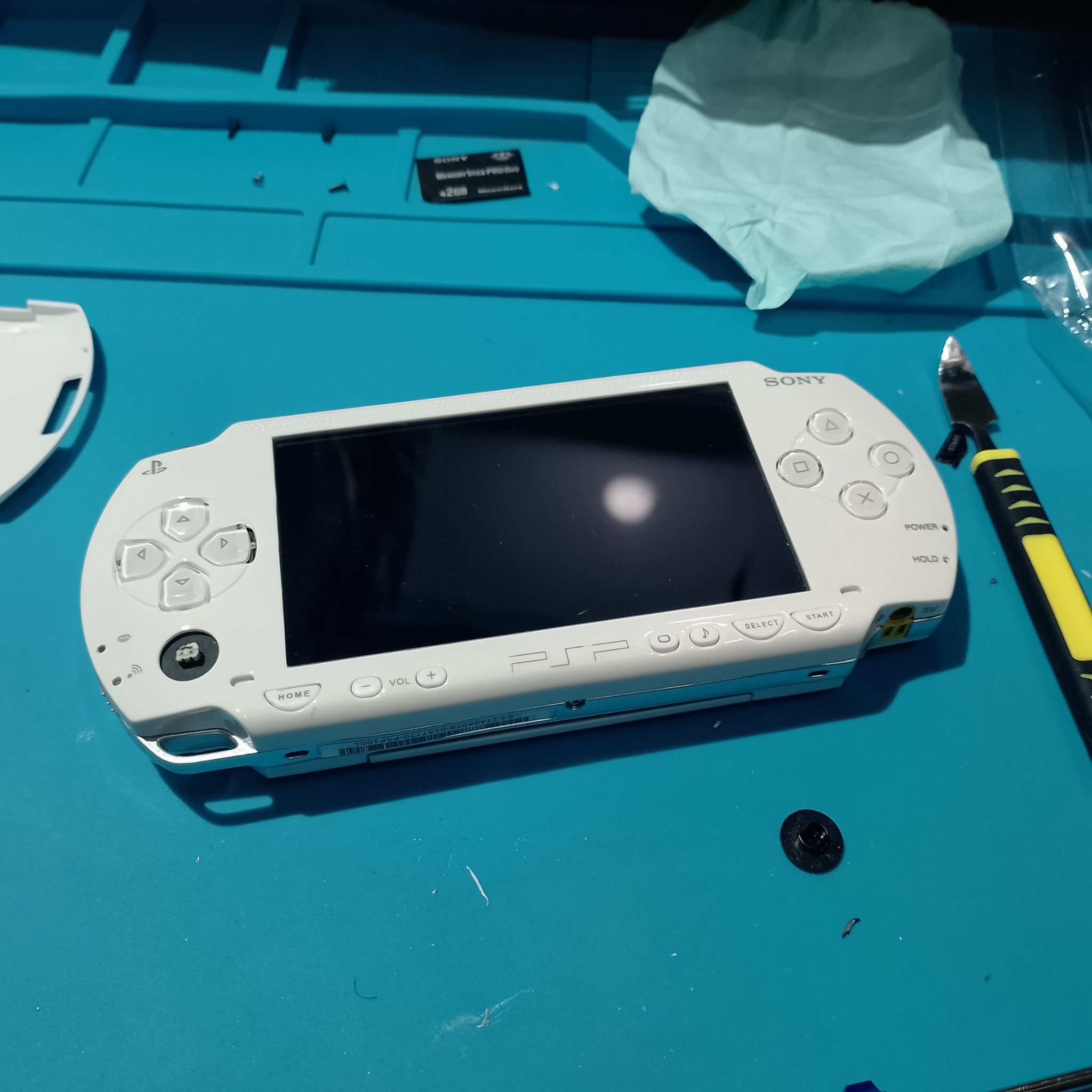PSP-1004 замена корпуса - Белая PSP лежит без аккумулятора. Перед закрытием батарейного отсека стоит проверить посадку новой АКБ и крышки.