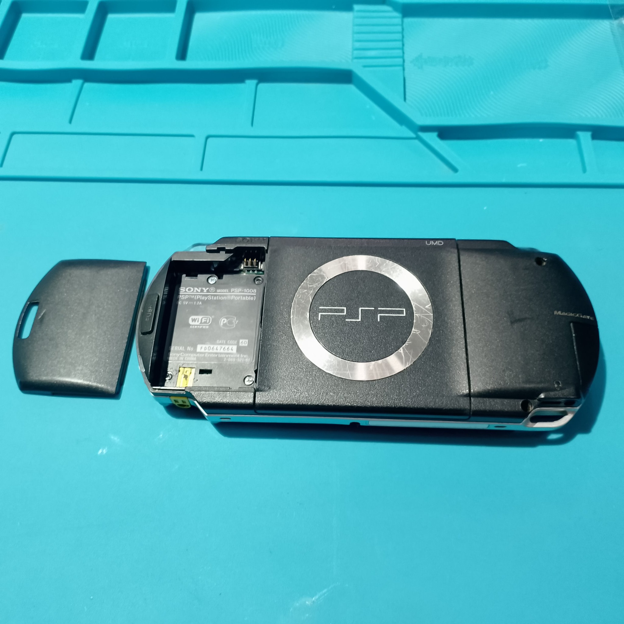 PSP-1004 замена корпуса - Старая чёрная задняя часть с открытым батарейным отсеком. Новая АКБ должна встать без давления и перекоса крышки.