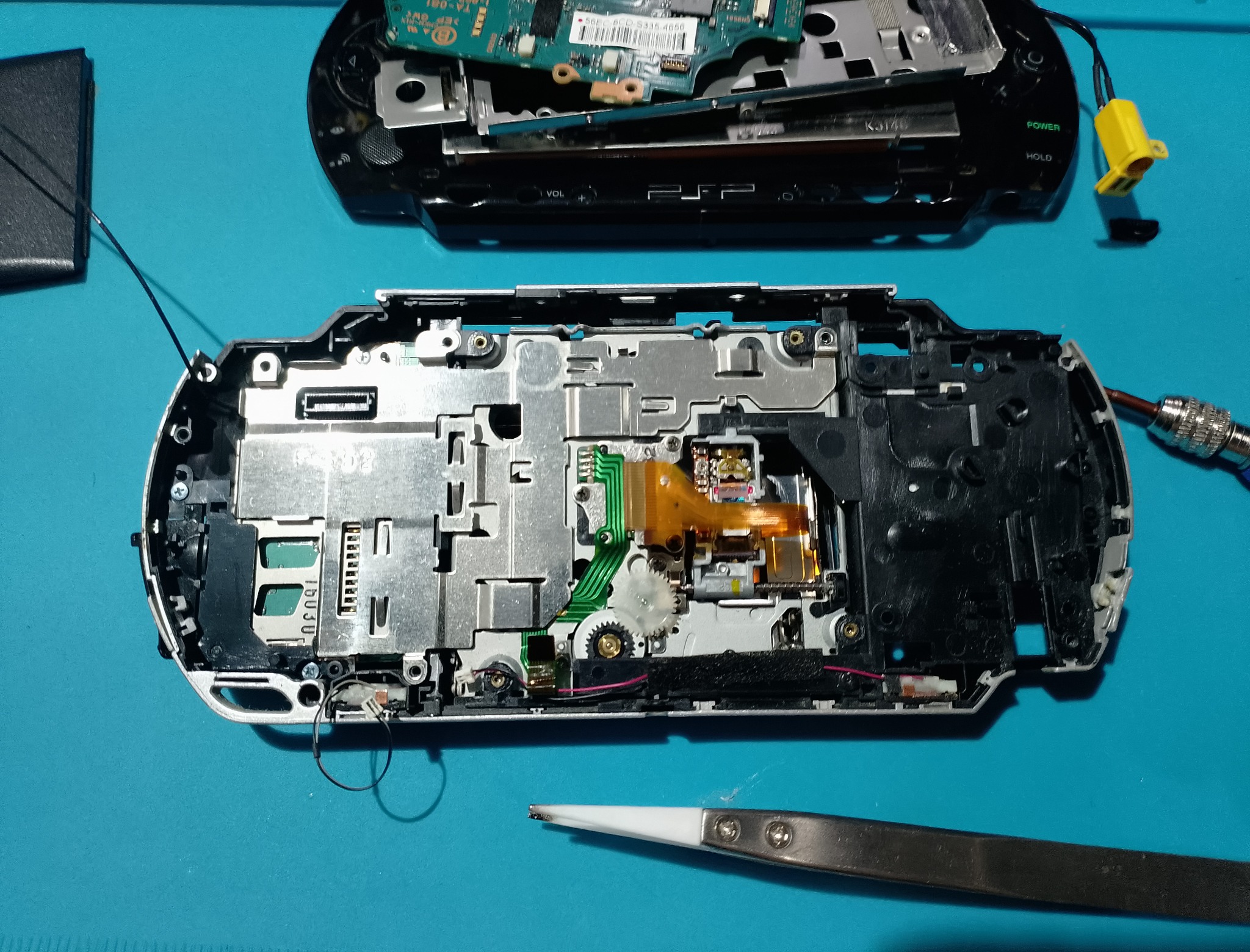 PSP-1004 замена корпуса - Корпус раскрыт, рядом видны шлейфы, экран и внутренние элементы. Перед сборкой полезно убрать пыль и проверить, что ничего не попало под рамку.