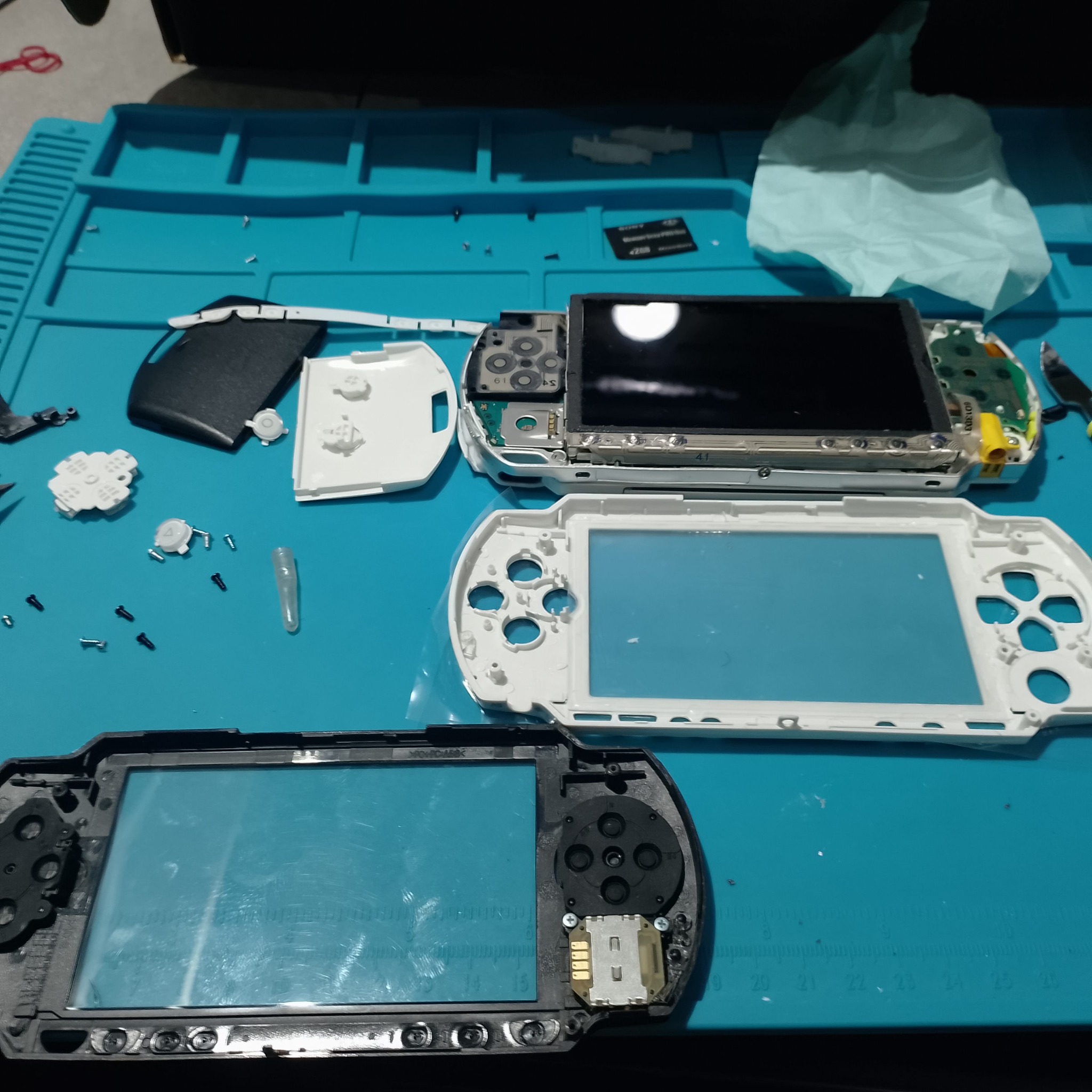 PSP-1004 замена корпуса - На столе сразу видны старый чёрный фронт, новая белая лицевая часть и разобранная консоль. Чёрная рамка уже потёрта, поэтому замена меняет не только цвет.